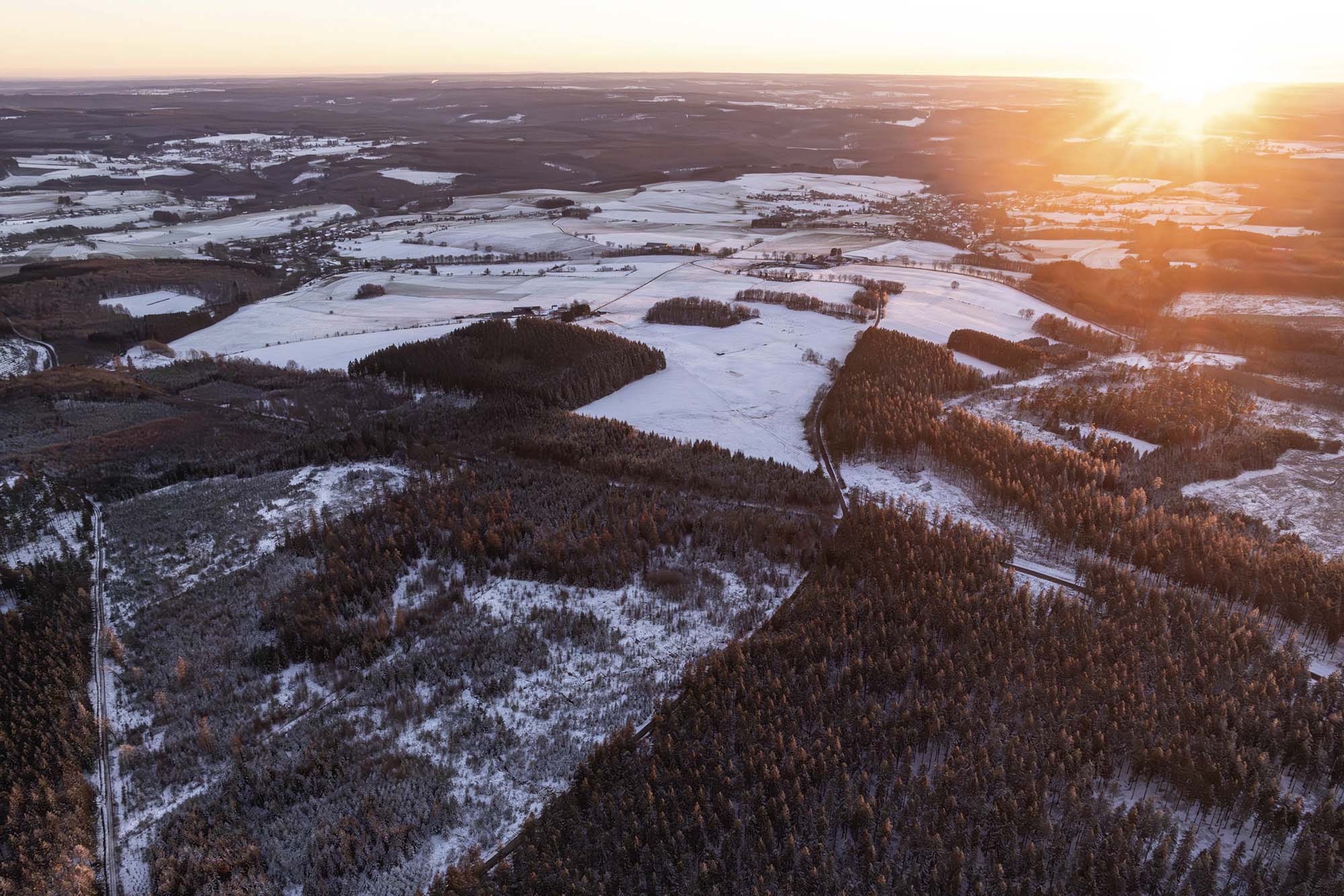Saint-Hubert au coucher du soleil avec forêts et plateaux enneigés en hiver