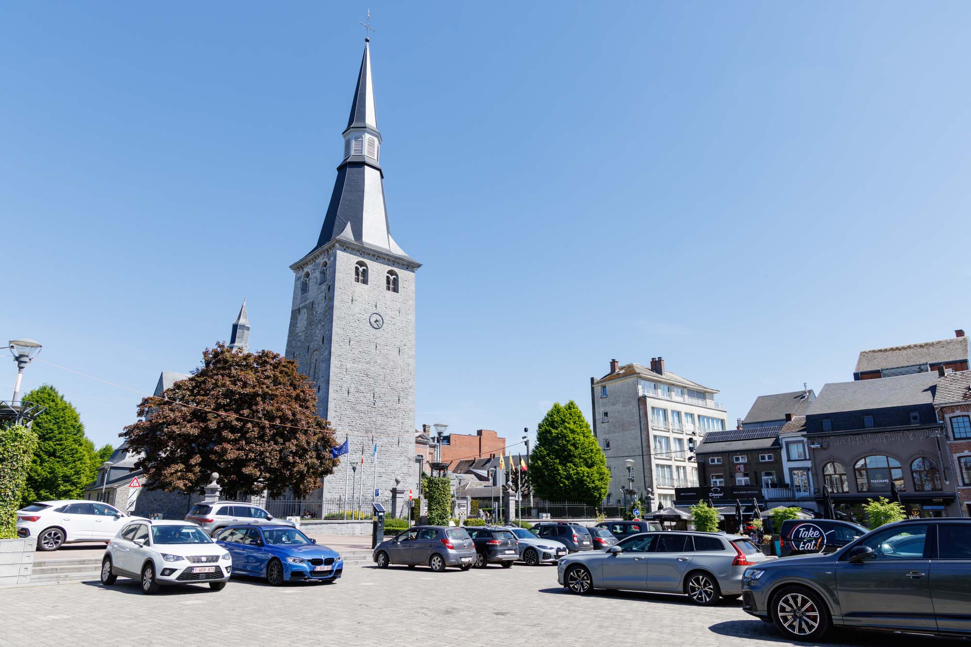 Clocher de l’église Saint-Nicolas et place centrale de Ciney par beau temps.