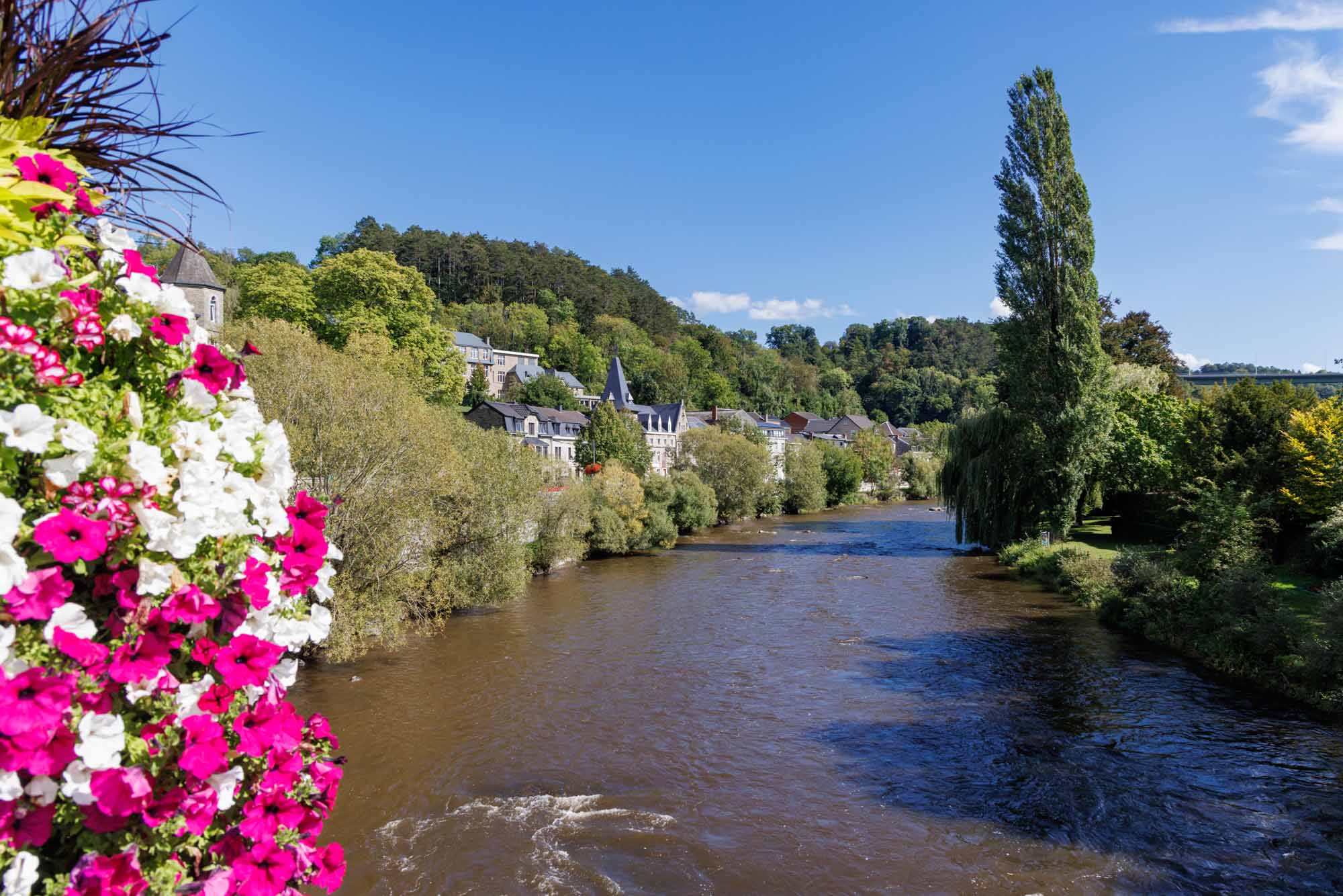 Remouchamps avec l’Amblève bordée d’arbres et maisons sous un ciel bleu