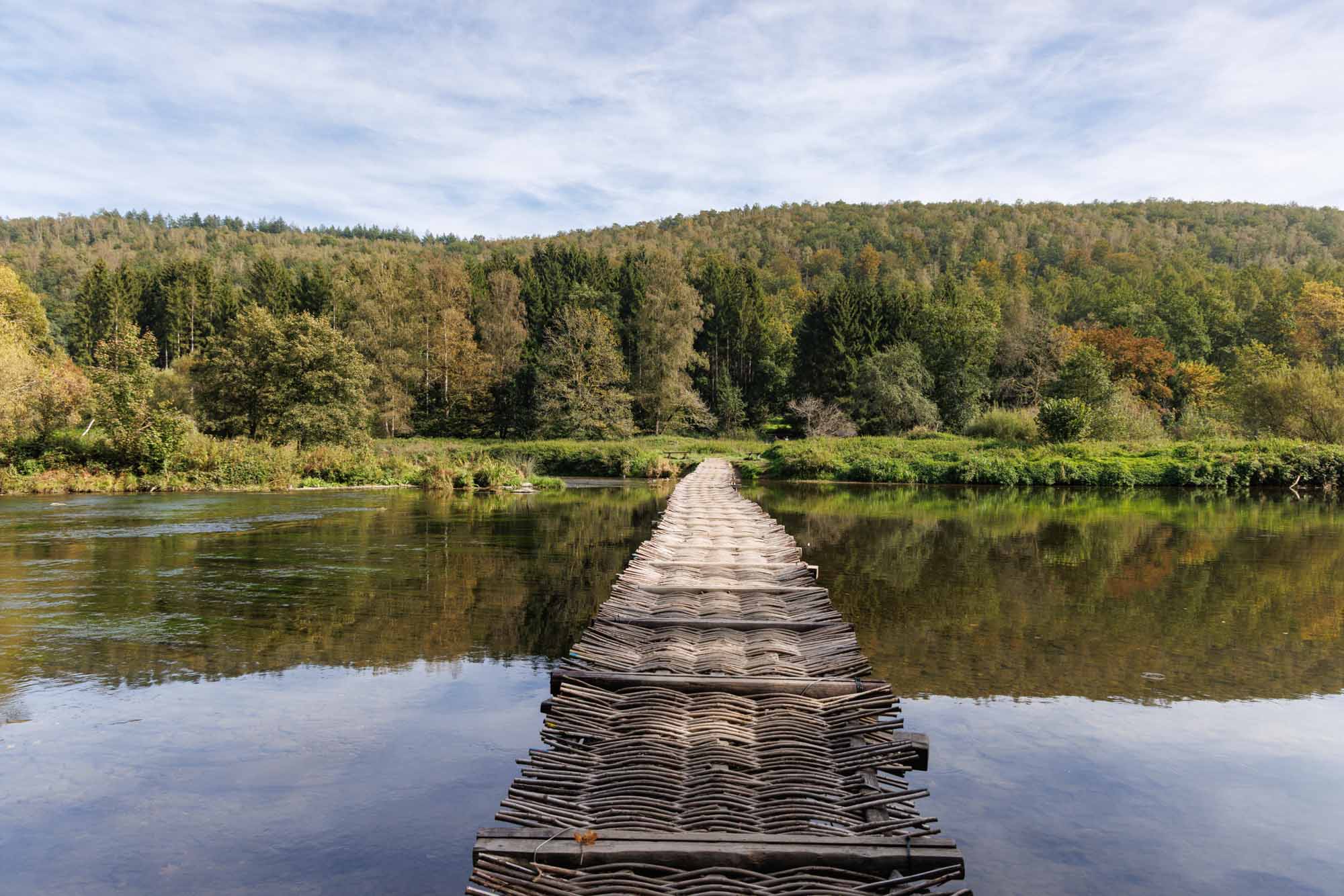 Le Pont des Claies traversant la Semois, passerelle en claies entourée d’un paysage forestier.