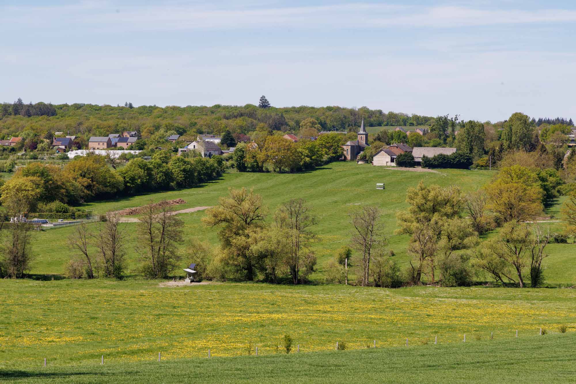 Vue panoramique sur le village d’Havrenne entouré de prairies et de forêts au printemps.