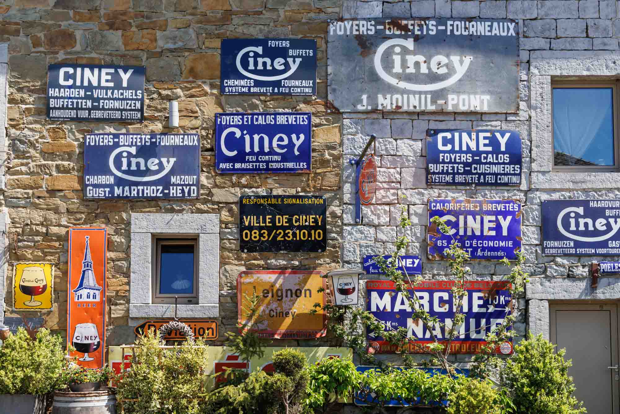 Anciennes enseignes publicitaires Ciney sur un mur en pierre, patrimoine urbain local.